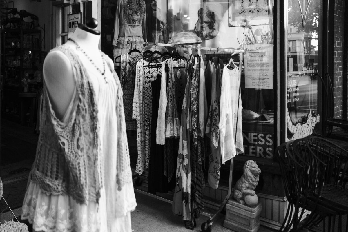 b/w image of clothing racks on the street in front of a store